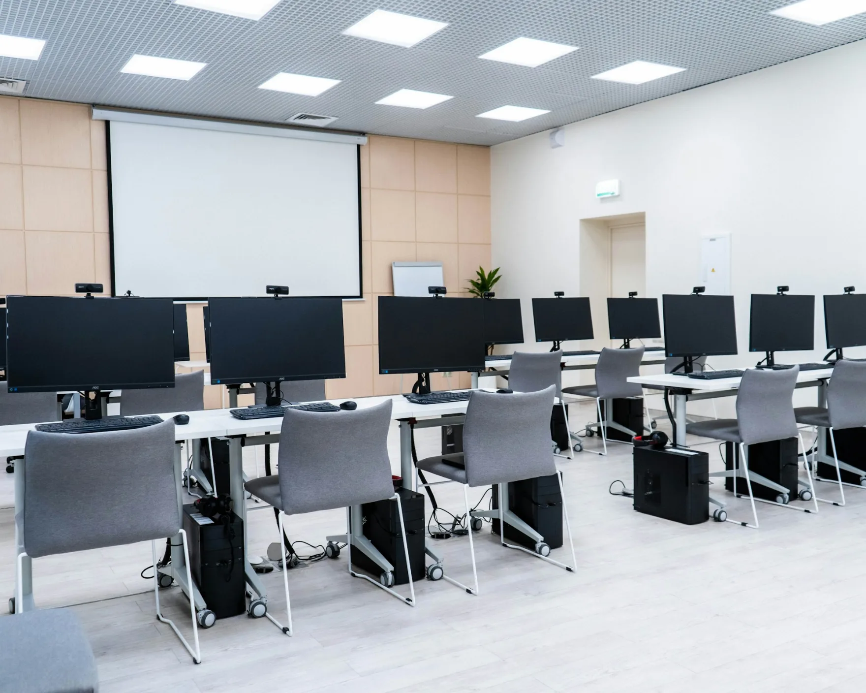 A training room with rows of desks and monitors facing a projector screen